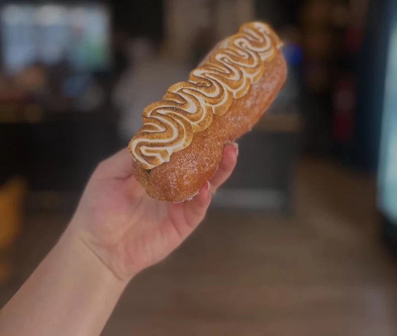 Hand holding a toasted meringue doughnut in a cafe