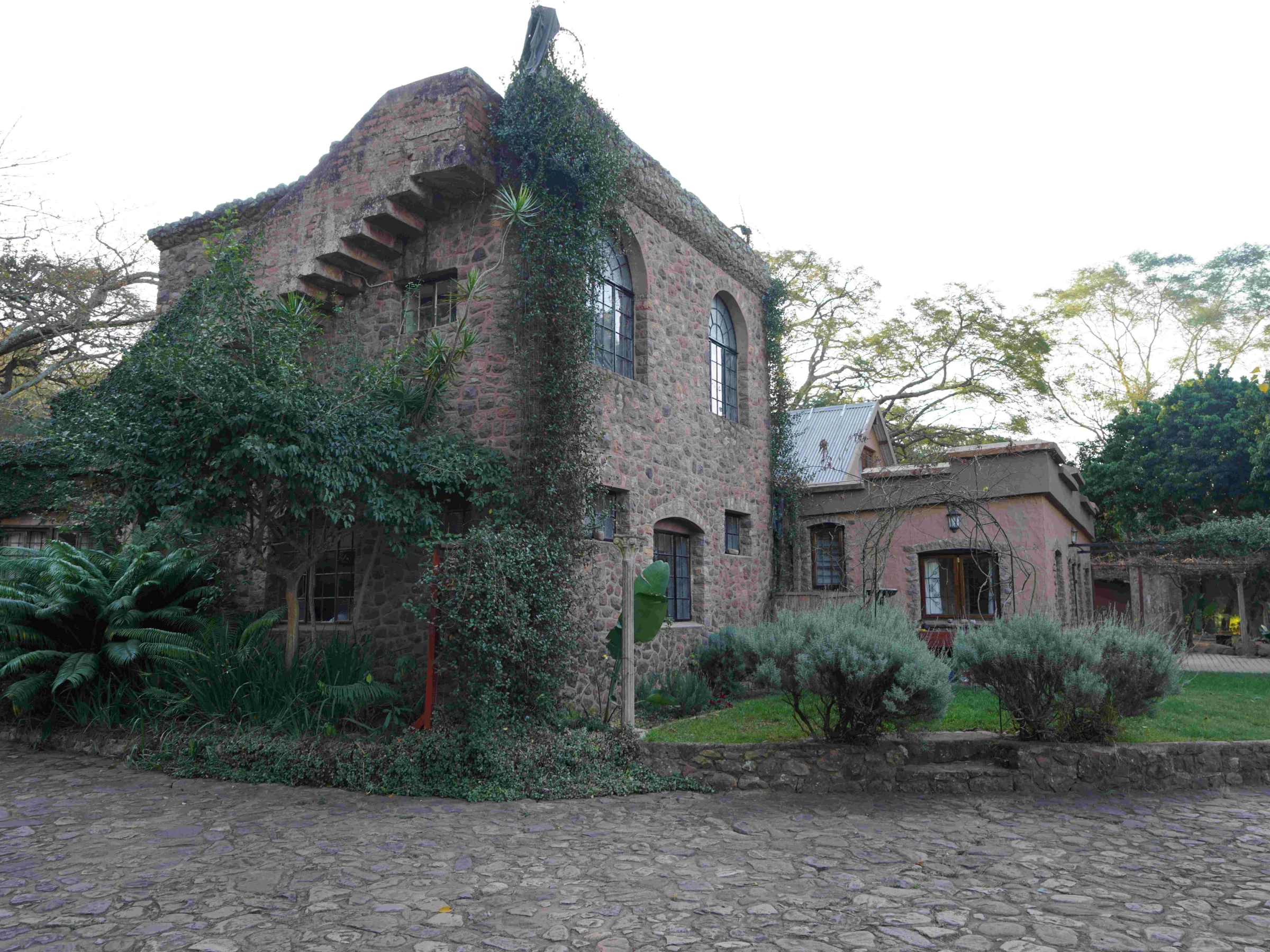 Ivy-covered stone building with arched windows and cobblestone courtyard